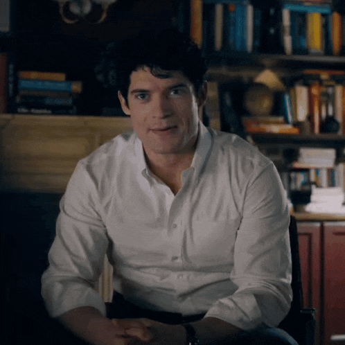 a man in a white shirt is sitting in a chair