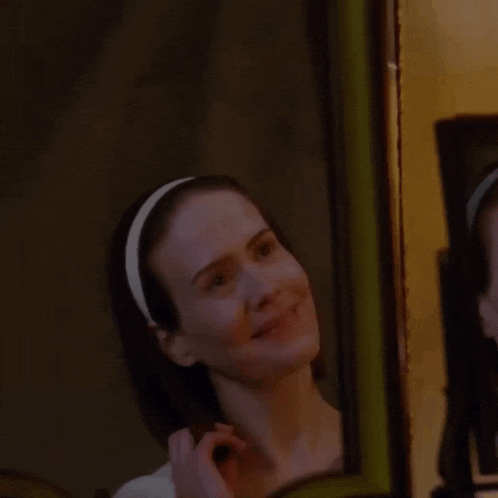 a woman is looking at herself in a mirror