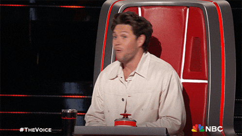 a man sits in a chair with a nbc logo on the back