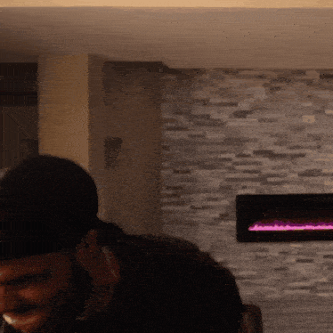 a man standing in front of a fireplace with a brick wall in the background