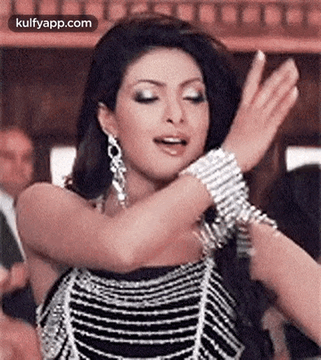 a woman in a black and silver dress is dancing with her arms outstretched .