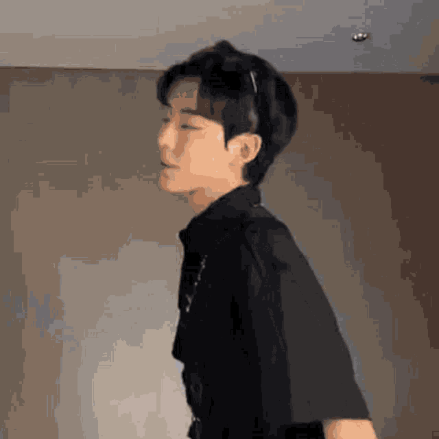 a young man wearing a black shirt is standing in a room .