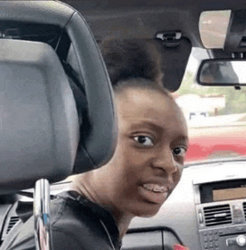 a woman is sitting in the driver 's seat of a car looking at the camera .