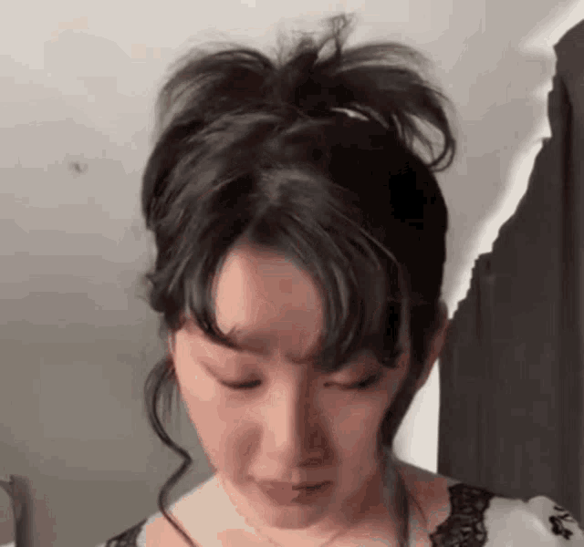 a woman with her eyes closed and her hair in a bun .