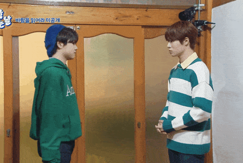 two young men standing next to each other in front of a sliding glass door with korean writing on it