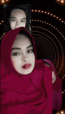 a woman wearing a pink hijab shows her tongue out