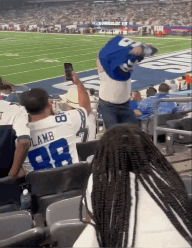 a man wearing a lamb jersey is taking a picture of a football game