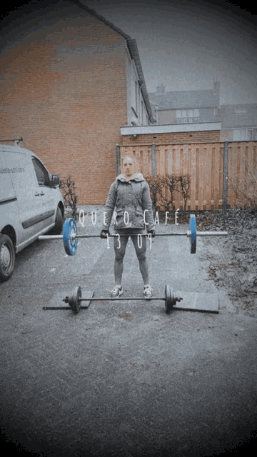 a woman is lifting a barbell in front of a van that says quexo cafe