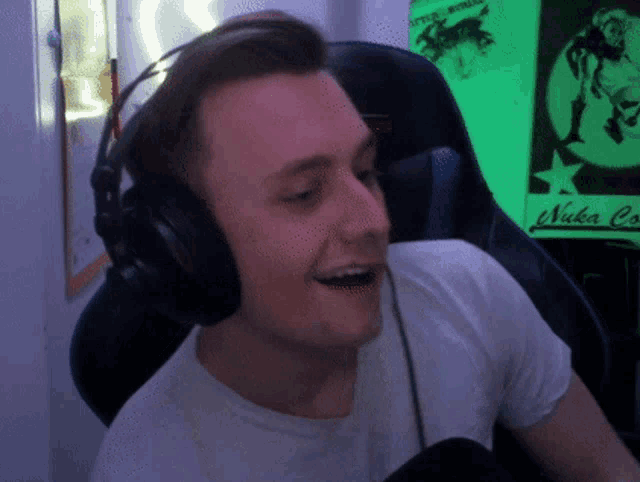 a man wearing headphones is smiling in front of a sign that says nuka cola