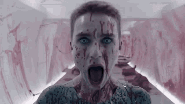 a woman with blood on her face is screaming and looking at the camera .