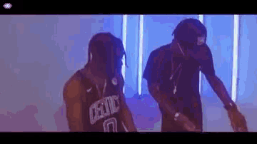 two men are standing next to each other in a room and dancing . one of the men is wearing a celtics jersey .