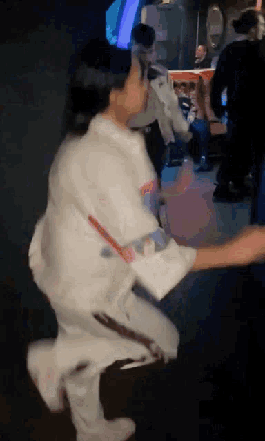 a person in a white shirt is holding another person 's hand in a dark room