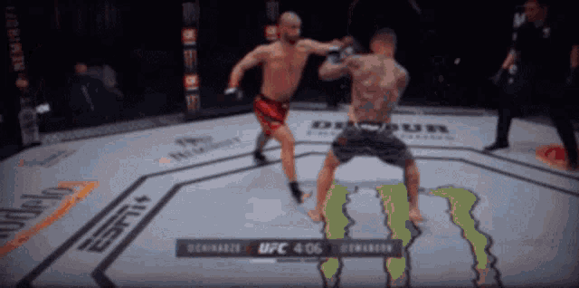 two men are fighting in a boxing ring with a monster energy logo on the ground