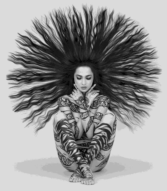 a black and white photo of a woman with long hair and tattoos on her body