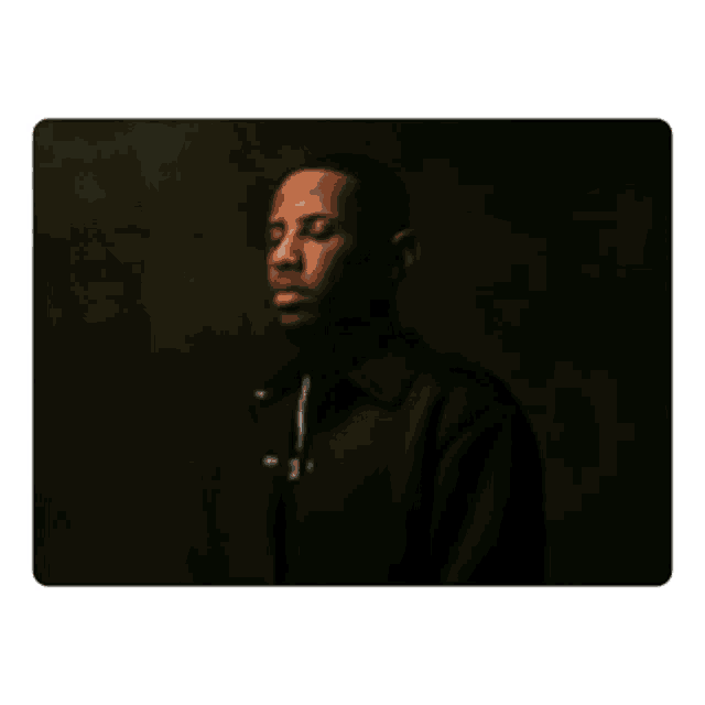 a man in a black jacket stands in a dark room