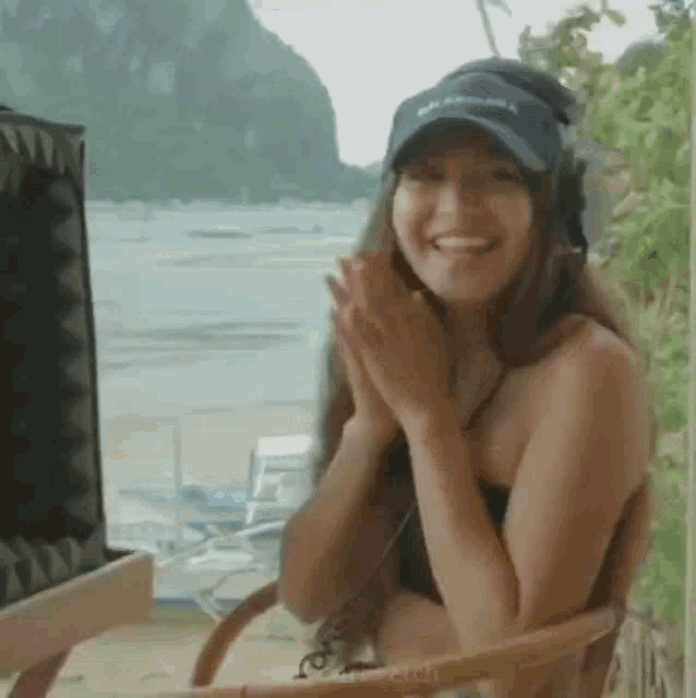 a woman in a bikini is sitting in a chair with her hands folded .