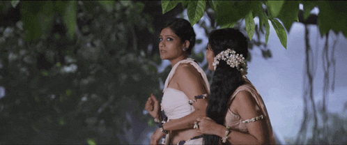 a couple of women standing next to each other in a forest