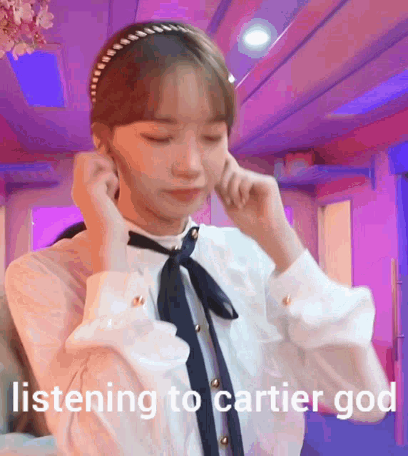 a girl is listening to cartier god and covering her ears with her hands