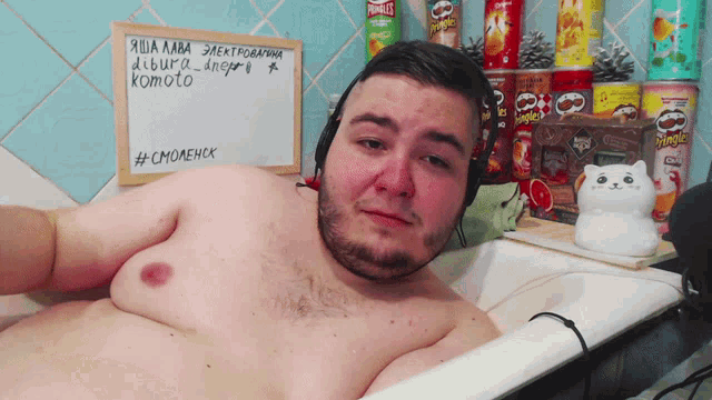 a man in a bathtub with a sign behind him that says #cmoaenck