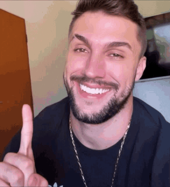 a man with a beard is smiling and giving the thumbs up sign