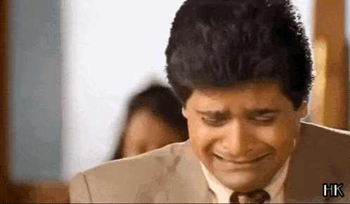 a man in a suit and tie is crying while a woman looks on