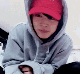 a person wearing a red hat and a hoodie is sitting on the floor .