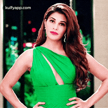 a woman in a green dress with her hands on her hips .