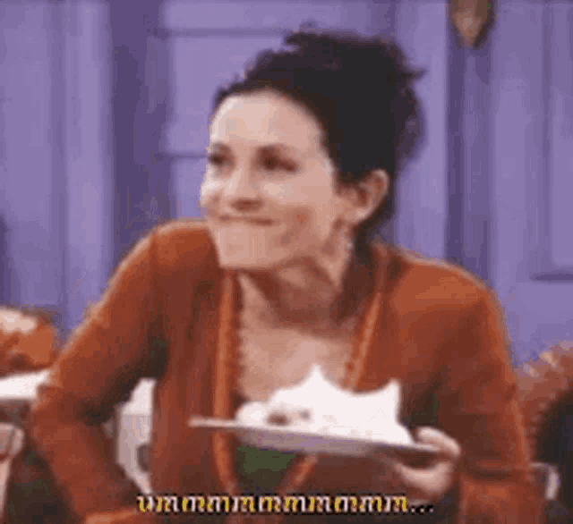 a woman is sitting at a table with a plate of food in her hand .