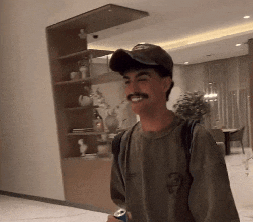 a man with a mustache wearing a hat and a t-shirt with a skull on it is smiling