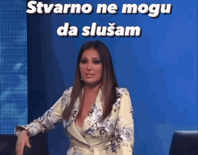a woman is sitting in front of a blue wall with the words " stvarno ne mogu da slusam " on it