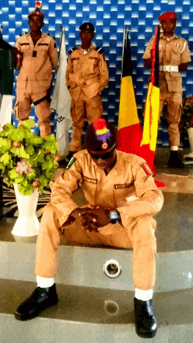 a man in a military uniform is sitting on a staircase with a flag in the background