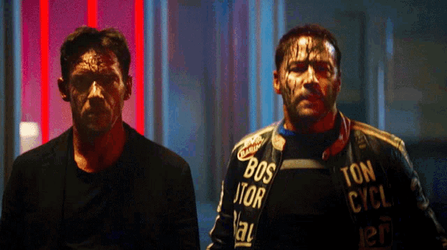 two men are standing next to each other with one wearing a jacket that says bos ator