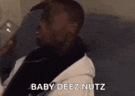 a man in a robe is sitting on a couch holding a glass of water and says `` baby deez nuts '' .