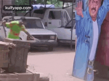 a man is standing in front of a billboard of a man waving his hand .