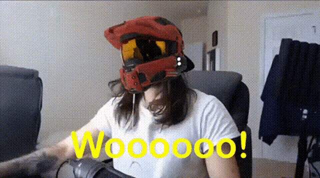 a man wearing a red helmet and goggles is sitting in a chair with the word woooo on the bottom