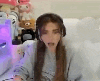 a woman wearing headphones is sitting in front of a computer and making a funny face .