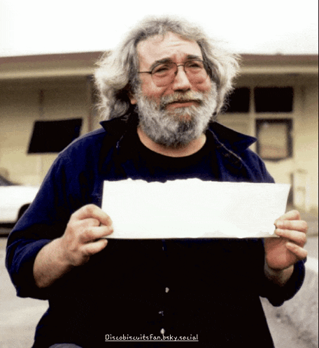 a man with a beard and glasses is holding a piece of paper in his hands