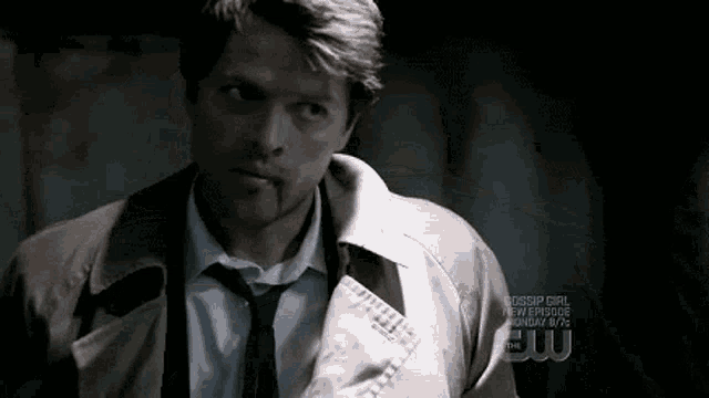 a man in a suit and tie is standing in a dark room with blood on his face .