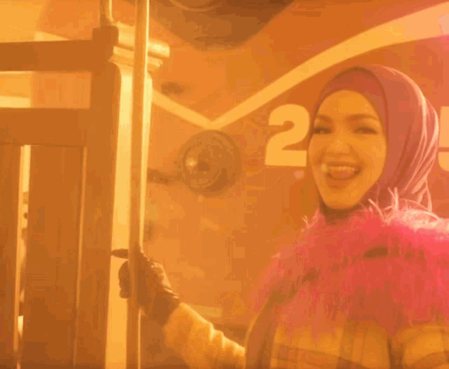 a woman in a purple hijab is standing in front of a bus with the number 25 on the side