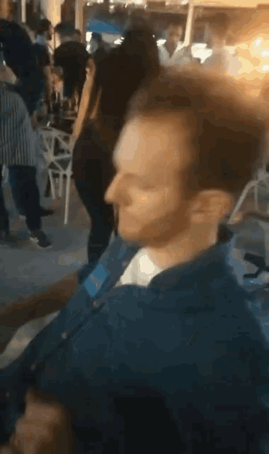 a man in a blue shirt stands in a crowd