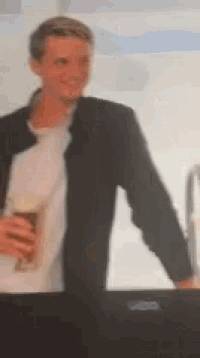 a man in a black jacket is holding a glass