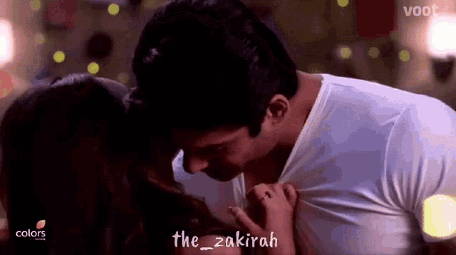 a man is kissing a woman on the forehead while wearing a white shirt