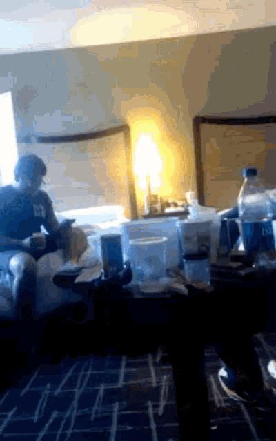 a man sits on a bed in a hotel room wearing a t-shirt that says ctn on it