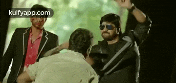 a group of men are standing next to each other . one of the men is wearing sunglasses .