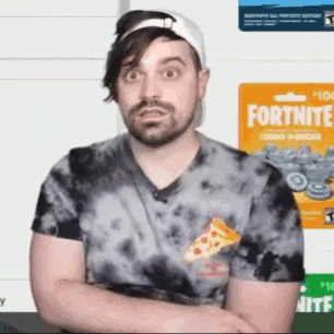 a man with a beard is wearing a tie dye shirt with a slice of pizza in the pocket .