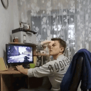 a man wearing a shirt that says ' a99ns ' on the back is sitting in front of a computer