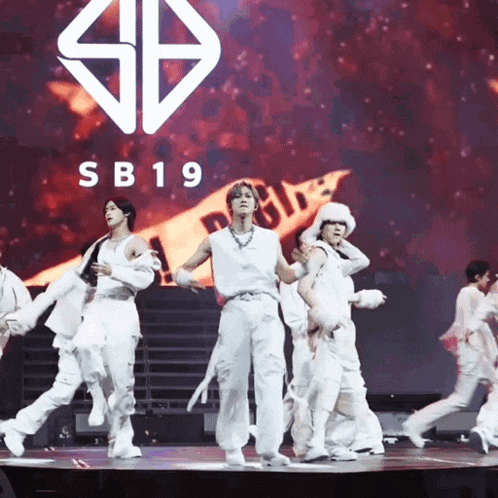 a group of young men are dancing on a stage with a sb19 logo in the background