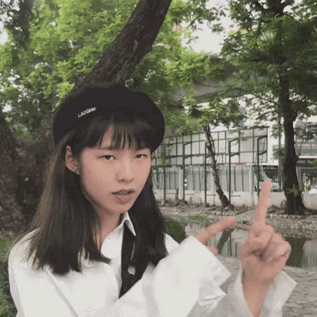 a girl wearing a lancome hat and a white shirt makes a peace sign