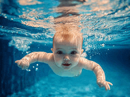 the baby is swimming underwater in the pool .