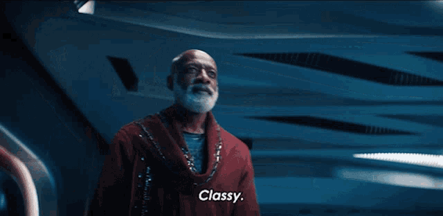 a man in a red cloak says classy in a dark room